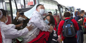 A medical worker,in red,embraces a colleague as she prepares leave Wuhan's main airport on Wednesday.