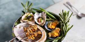 A mini seafood tower holding oysters with finger lime,barbecued abalone skewers and mussel escabeche.