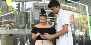 Ranish Kromodoyo and Anya Absalom struggle to make a call outside an Optus store.