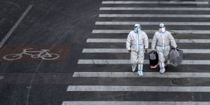 Epidemic control workers wear PPE to prevent the spread of COVID-19 as they walk across a road in an area with communities in lockdown in Beijing,China.