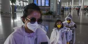 BEIJING,CHINA - MARCH 24:A Chinese family wear protective masks,sunglasses and raincoats after arriving on a flight at Beijing Capital International Airport.