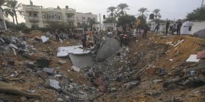 Palestinians inspect the damage of a destroyed house that was hit by an Israeli airstrike.