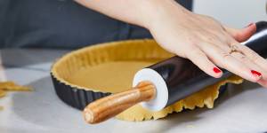 Trim excess pastry from the tart shell by running a rolling pin over the tin.