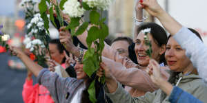 Women wave flowers as they join protest against the Belarus election results on August 13.