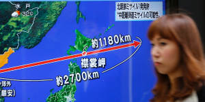 A woman walks past a TV screen in Tokyo broadcasting news of North Korea's recent missile launch.