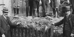 Men pose in front of the picket fence unearthed in the early 1920s during excavation work for the Capitol Theatre on Swanston Street.