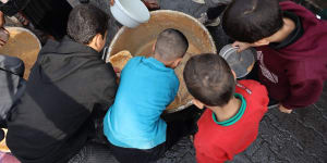 Palestinian children collect free food handouts from a volunteer hospice in Rafah,southern Gaza.