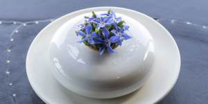 A tiny avocado tart is dotted with borage flowers and brightened with finger lime.