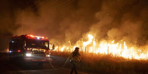 A firefighter watches flames approach Gilman Springs Road during the Rabbit Fire late on Friday,in Moreno Valley,California.