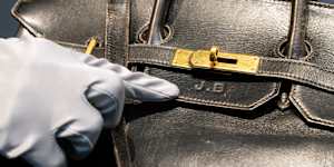 An auction worker points to Jane Birkin’s initials on the original Birkin bag created by Hermès in 1984.