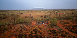 Uluru in the distance covered by cloud as guests gather for Field of Light.