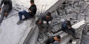 Palestinians sit by the building of the Al-Nadi family destroyed in the Israeli bombardment of the Gaza Strip in Nusseirat refugee camp.