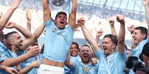 Matheus Nunes holds the Premier League trophy aloft as Manchester City celebrate their title victory.