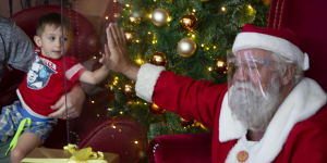 A child greets Santa through a plastic shield in a shopping centre in Johannesburg,South Africa.