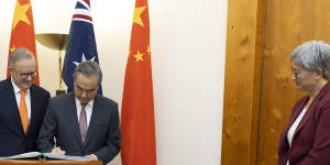 Prime Minister Anthony Albanese,Chinese Foreign Minister Wang Yi and Foreign Affairs Minister Penny Wong,during the signing of the visitors book.