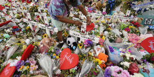 A visitor places bracelets on crosses at a memorial as he and others pay their respects to the victims killed in the Robb Elementary School shooting.