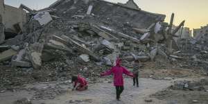 Palestinian children play next to a building destroyed by Israeli army strikes in the central Gaza Strip town of Khan Younis on January 1.