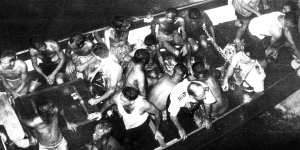 Survivors picked up by naval rescue craft prepare to board the aircraft carrier. 