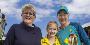 Former Australian World Cup cricketer Margaret Jennings,junior fan Annabel Archer,and Ellyse Perry from the current Australian cricket team pose for a photograph with the ICC World Cup,Ashes and ICC T20 trophies. 