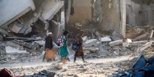 People walk through destroyed buildings on Sunday after the IDF pulled out of Khan Younis.