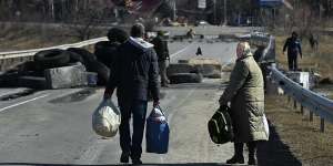 Local residents walk towards their home over a destroyed bridge laid with anti tank mines,east of Kyiv,Ukraine.