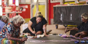 On the canvas,from left:Tuppy Goodwin,Puna Yanima,Sally Scales and Iluwanti Ken collaborate at Mimili Maku Arts. Yaritji Young’s husband Frank sits on the chair.