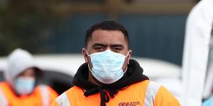 A security guard poses for a photograph as nurses test people arriving at a COVID-19 testing facility in Otara,Auckland.