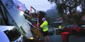 Men load rubbish into a truck that collects residential waste along Macauley street in Leichhardt.