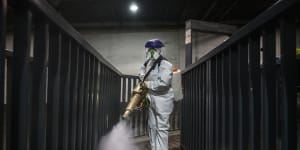A volunteer fumigates a bus station in Beijing. Experts are now looking to the economic ramifications of the coronavirus. 