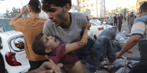An injured Palestinian boy is carried from the ground following an Israeli airstrike outside the entrance of the al-Shifa hospital in Gaza City.