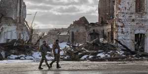 Ukrainian servicemen walk by a building destroyed by a Russian strike in Kupiansk on Monday.