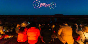 People watch Wintjiri Wiru light up the night sky above Uluru.