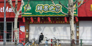 A security guard sits in front of closed stores in a locked down Shanghai neighbourhood. 
