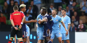 Victory’s Adama Traore is held back by a City player after receiving his red card.