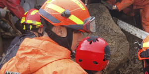 Rescue workers search for people in a house collapsed from a landslide caused by heavy rain in Yeongju,South Korea,on Saturday.