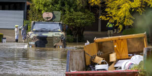 An Australian Army Bushmaster Protected Mobility Vehicle drives through a flooded street in McGrath Hills near Windsor.
