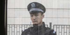 A police officer seen through a train window in Turpan,Xinjiang,in 2018.