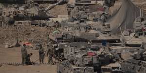 Israeli soldiers work on a tank in a staging area near the Israeli-Gaza border in southern Israel on Monday.