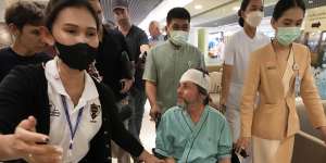 An Australian passenger,center,who was injured on a flight that was battered by severe turbulence,talks to reporters at Samitivej Srinakarin Hospital in Bangkok,Thailand. 