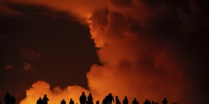 Onlookers watch the volcanic activity from a distance on Saturday night.