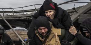Ukrainian forces carry an elderly man as thousands flee Irpin on Monday.
