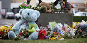 Flowers and toys at the base of a statue near the crash scene. 