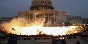 An explosion caused by a police munition is seen while supporters of US President Donald Trump gather in front of the US Capitol Building.