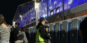 A research assistant queues at the portaloos,where discarded drugs were often found.