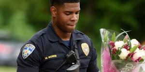 Baton Rouge Police Department Officer Markell Morris holds a bouquet of flowers and a Superman action figure that a citizen left at the Our Lady of the Lake Hospital.
