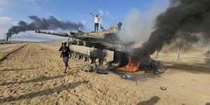 Palestinians celebrate by a destroyed Israeli tank at the Gaza Strip fence east of Khan Younis on October 7. 