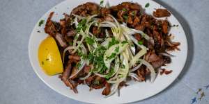Slow-cooked lamb gyros with raw onion slices and lemon.