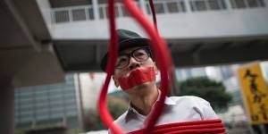 A protester stands in front of a noose that reads:"Kidnapping"during a protest against the disappearance of five booksellers in Hong Kong in 2016.