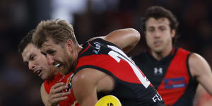 Essendon’s Dyson Heppell clashes with Gold Coast’s Ben Ainsworth before he was subbed out of the game.
