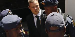 South African Olympic and Paralympic sprinter Oscar Pistorius (centre) is escorted to a police van after being sentenced.